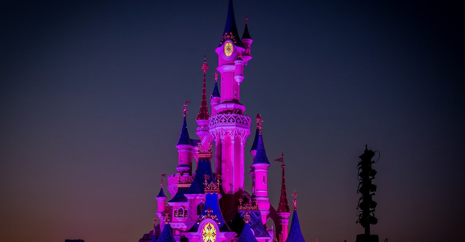 Sleeping Beauty Castle im Disneyland Paris bei Nacht - das Schloss ist in Pink angestrahlt
