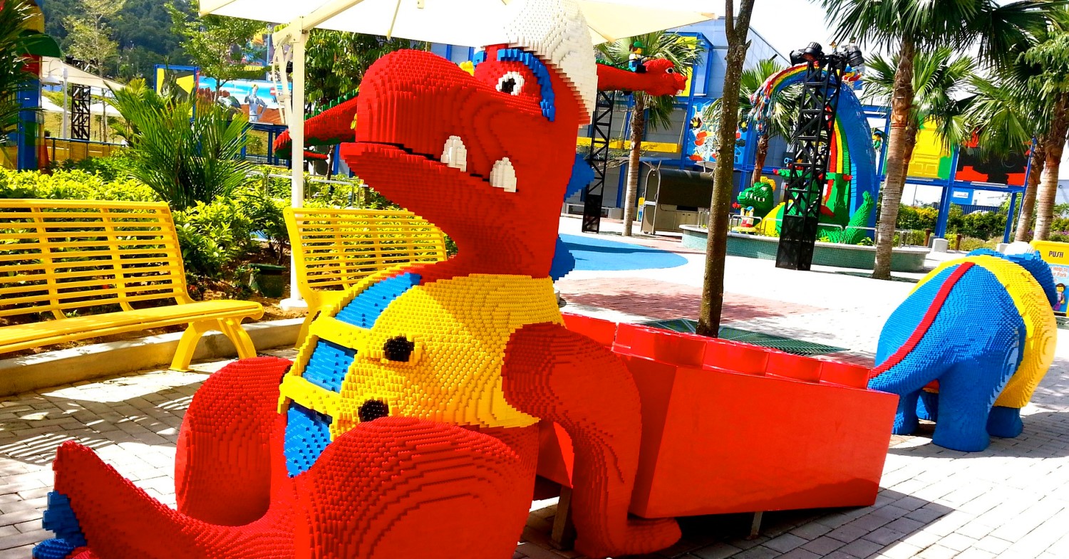 Riesige Figur aus Legosteinen: ein roter Drache, der eine gelbe Weste und einen weißen Helm trägt