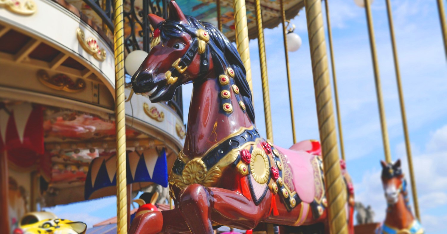 Traditionelles Pferdekarussel mit goldfarbenem Gestänge und einem schwarzen Schlachtross
