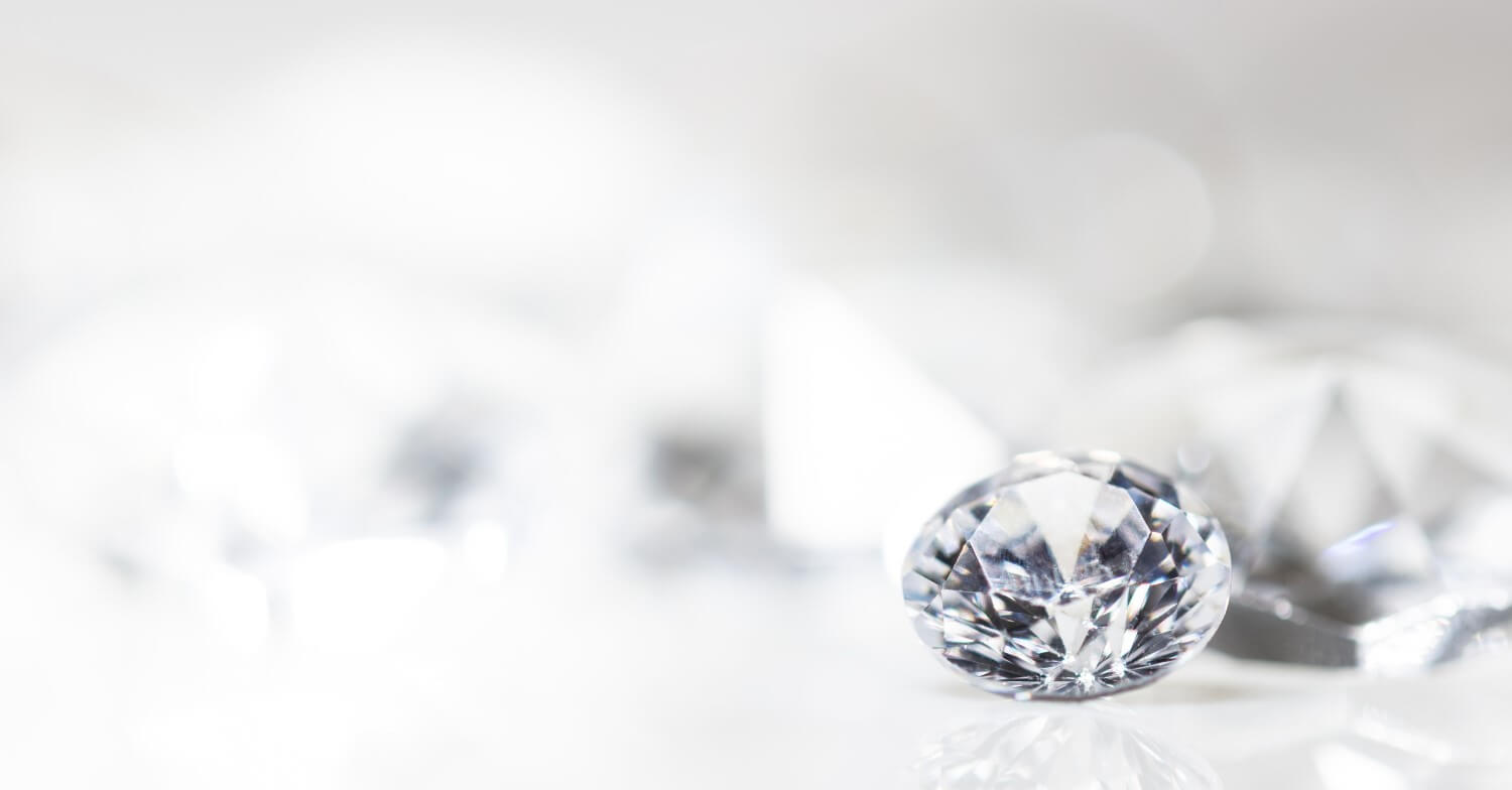 Ein schimmernder Diamant vor einem reflektierenden Hintergrund fotografiert