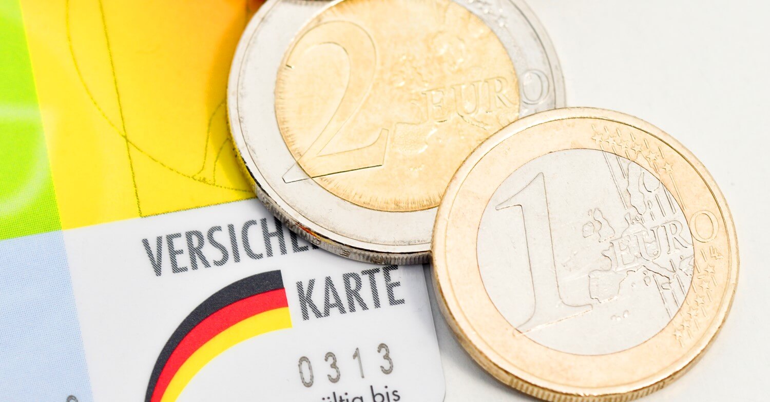 Eine Versichertenkarte der gesetzlichen Krankenkasse, darauf liegen eine 1 Euro-Münze und eine 2 Euro-Münze