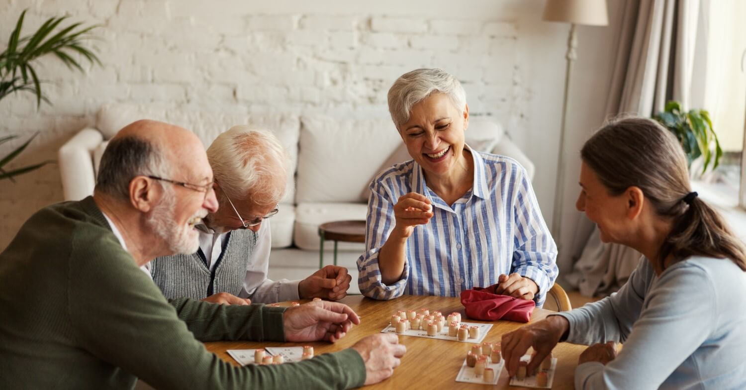 Eine Gruppe Senioren sitzt an einem Tisch und spielt Bingo